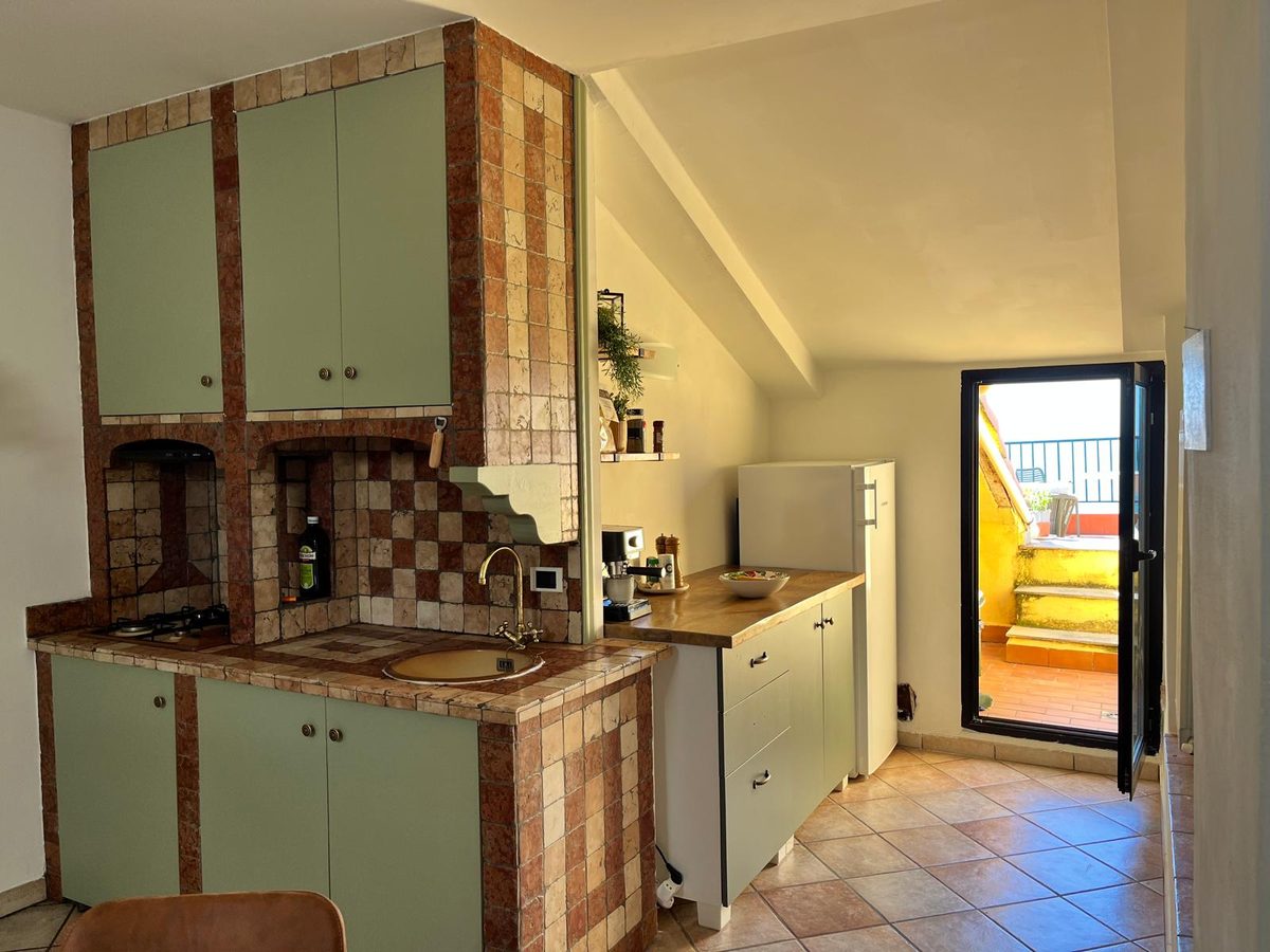 Keuken met groene kasten en doorgang naar het terras
