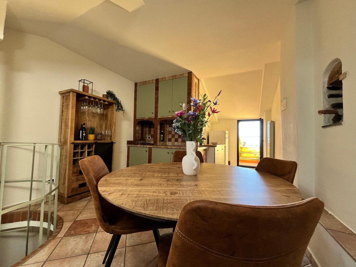 Woon- en eetruimte met ronde mangohouten tafel en wijnkast